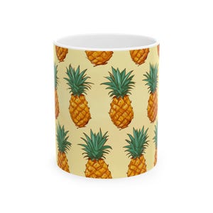 Puede incluir: Taza de cerámica blanca con un patrón repetido de piñas ilustradas. Las piñas son de color amarillo-naranja con copas verdes y frondosas, sobre un fondo amarillo claro. Un diseño divertido y tropical para una taza de café o té.
