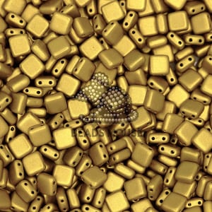 May include: A close-up image of a pile of small, square, gold-colored beads. The beads have a matte finish and are made of glass.