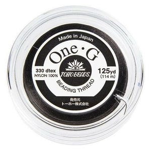 May include: A clear plastic container holding black beading thread. The label reads "One G" with "TOHO BEADS" and "125 yd (114 m)". The text "Made in Japan" and "BEADING THREAD" are also visible.