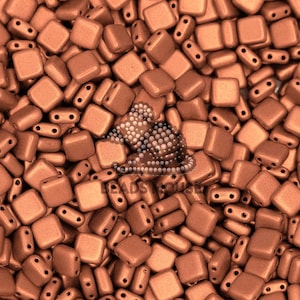 May include: A close-up view of a large quantity of small, square, copper-colored beads. The beads have a matte finish and are arranged in a random pattern.