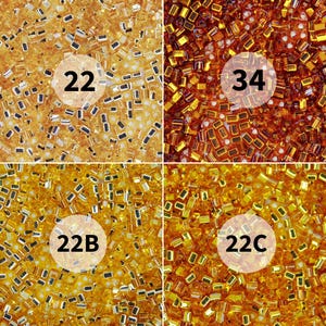 May include: Close-up of four sections of small, rectangular beads in shades of gold and brown. Each section has a white circle with a number and/or letter combination: 22, 34, 22B, and 22C. The beads are densely packed, creating a textured appearance.