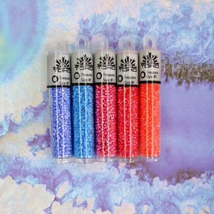 May include: Five clear tubes filled with small, colourful beads. The tubes are labelled "TOHO Treasure Size #1" and contain blue, pink, and orange beads. The beads are tightly packed, creating a vibrant display of colour. Ideal for jewellery making and crafts.