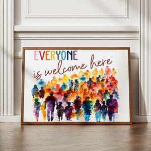 Peut inclure: Une affiche encadrée avec les mots "EVERYONE is welcome here" en lettres colorées. L'œuvre d'art présente une représentation à l'aquarelle d'une foule de personnes de différentes couleurs, créant une atmosphère accueillante.