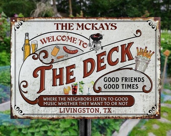 Może przedstawiać: Rustykalny metalowy znak z białym tłem i brązowym tekstem, który brzmi "The McKays Welcome to The Deck Good Friends Good Times Where the Neighbors Listen to Good Music Whether They Want to or Not Livingston, TX". Znak zawiera ilustracje grilla, butelek piwa, hot doga i napojów.