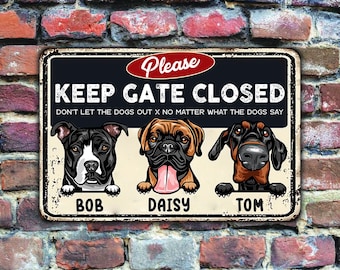 May include: Metal sign with the text "KEEP GATE CLOSED" and the phrase "DON'T LET THE DOGS OUT X NO MATTER WHAT THE DOGS SAY." Features illustrations of three dogs named Bob, Daisy, and Tom. The sign is set against a brick wall.