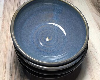 May include: A stack of three ceramic bowls featuring a speckled blue interior glaze with a smooth, dark brown exterior. The top bowl displays a visible circular pattern at the base and a distinct, slightly darker rim, showcasing a handcrafted aesthetic.