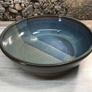 May include: A large, blue and white ceramic bowl with a speckled glaze. The bowl has a wide rim and a rounded bottom.