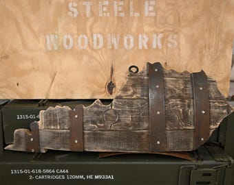 May include: A wooden wall art piece shaped like the state of Virginia. The wood is dark brown and has a rustic look. The state is outlined with metal bands. The piece is hanging on a wall with a green military crate below it. The crate has text on it that reads: "1315-01-618-5864 CA44 2- CARTRIDGES 120MM, HE M933A1 W/FUZE M783 FOR MORTARS M120/M121 LOT GDL19L024-002 WT 97.40 LBS".