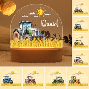 Könnte beinhalten: Personalisiertes Nachtlicht mit einer Aquarellillustration eines Traktors in einem Weizenfeld. Der Name "Daniel" ist in Schreibschrift geschrieben. Der Sockel ist aus Holz, die Oberseite aus klarem Acryl mit Sonne und Wolken.