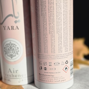 May include: A pink and white air freshener bottle with the brand name "YARA" and the text "Air Freshener" on the front. The back of the bottle lists the ingredients, safety information, and manufacturing details. The bottle is labeled "Ozone Friendly, No CFC" and "Manufactured by: Lattata Perfumes Industries LLC., United Arab Emirates. Made in UAE."