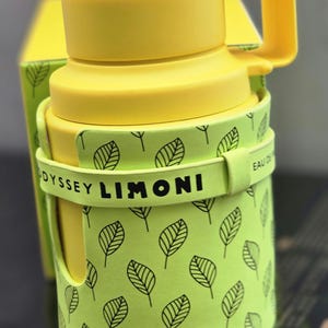 May include: A yellow cylindrical bottle with a green leaf pattern and a black band that says "ODYSSEY LIMONI EAU DE PARFUM".