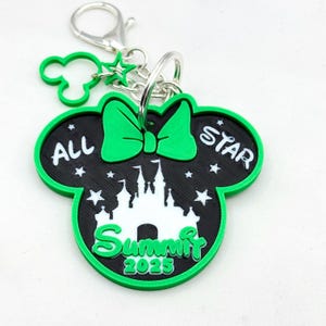 May include: Green and black Mickey Mouse-shaped keychain with a white castle silhouette, stars, and the text "All Star Summit 2025".