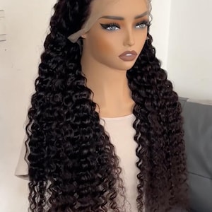May include: A mannequin head displays a deep curly wig. The wig is dark brown with long, voluminous curls. The text on the image reads "Deep Curly 13x4 Wig 250% 32inch 380g". The wig is designed to look natural.