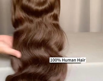 Könnte beinhalten: Eine braune, gewellte Perücke aus 100 % Echthaar. Das Haar hat eine satte, warme braune Farbe mit einem natürlichen Wellenmuster. Die Perücke wird von den Händen einer Person gehalten. Der Text "100% Human Hair" ist sichtbar.