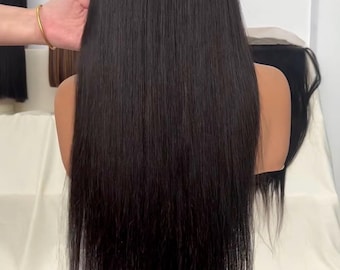 May include: A long, straight black wig on a mannequin head. The hair is sleek and shiny, with a natural texture. The wig is displayed on a stand against a white backdrop.