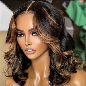May include: A woman with long, wavy hair styled in a layered bob. The hair is a mix of dark brown and light brown, creating a highlighted effect. The hair is styled with loose waves and curls.