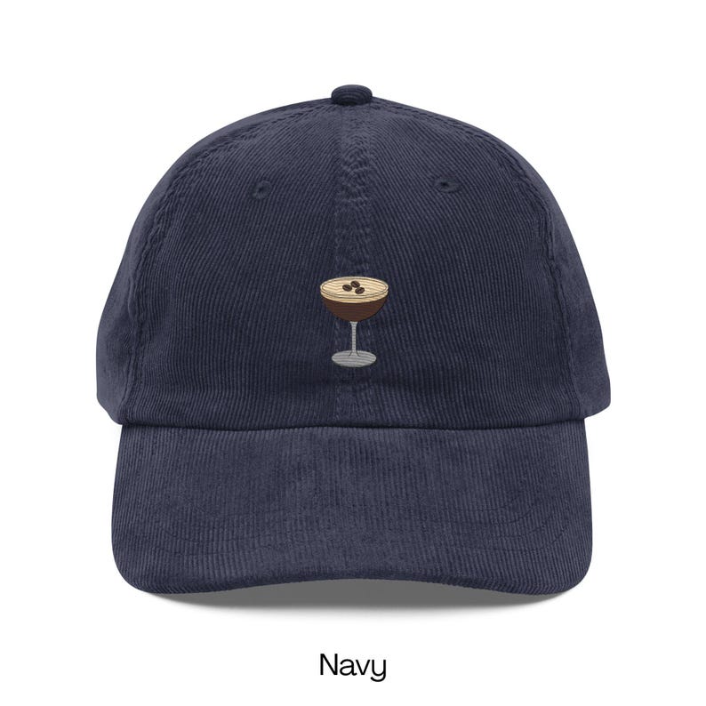May include: Navy blue corduroy baseball cap with an embroidered cocktail glass design. The cocktail glass has a brown drink with three coffee beans on top. The word "Navy" is printed at the bottom of the image.