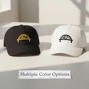 May include: Two baseball caps, one black and one white, each featuring a bridge design with the number "4121" embroidered on the front. The black cap has a yellow bridge, while the white cap has a black bridge. The text "Multiple Color Options" is below.
