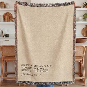 May include: A woven throw blanket in a light beige color featuring a fringed edge and black text that reads: AS FOR ME AND MY HOUSE, WE WILL SERVE THE LORD. JOSHUA 24:15. The blanket has a textured appearance with a multi-colored woven border.