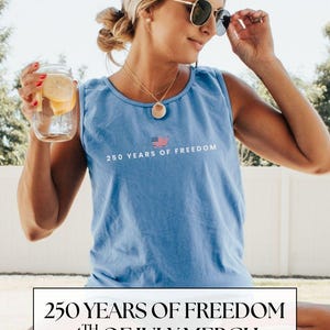 May include: A light blue tank top with the text "250 YEARS OF FREEDOM" and an American flag graphic. The image also includes a person wearing sunglasses and holding a glass jar with lemon slices.