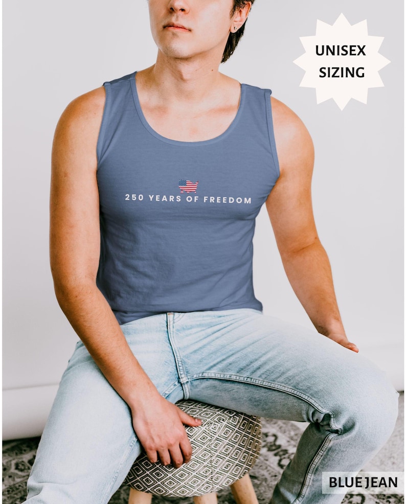 May include: A blue tank top with the text "250 YEARS OF FREEDOM" and a small American flag graphic. The tank top is a solid blue color. The words "UNISEX SIZING" are in a white starburst shape. The words "BLUE JEAN" are in a white rectangle.