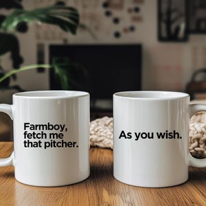 May include: Two white ceramic mugs with black text. The mug on the left says "Farmboy, fetch me that pitcher." The mug on the right says "As you wish."