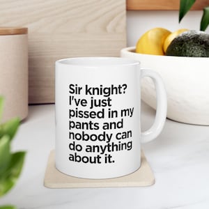 May include: White ceramic mug with black text that reads "Sir knight? I've just pissed in my pants and nobody can do anything about it."