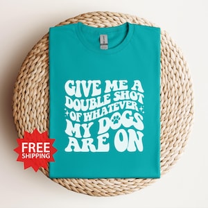 May include: A turquoise blue t-shirt with white text that reads "Give me a double shot of whatever my dogs are on".