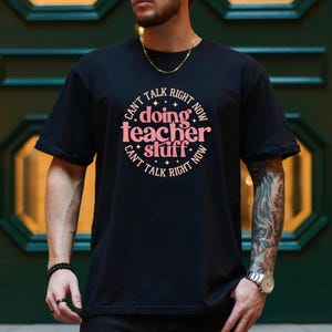 May include: Black t-shirt with a pink circle graphic that says "Can't talk right now doing teacher stuff Can't talk right now".