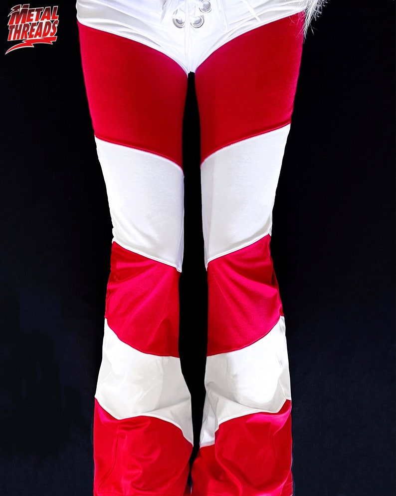 May include: Red and white striped pants with a white waistband and a drawstring closure. The pants are made of a stretchy fabric and have a wide leg.