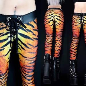 Puede incluir: Leggings de estampado de tigre naranja y negro con una cintura de cuero negro y un detalle de encaje en la parte delantera.