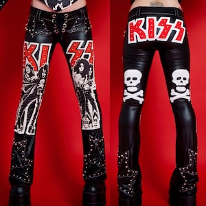 May include: Black leather pants with a KISS logo and skull and crossbones design. The pants have a lace-up front and star-shaped embellishments on the legs. The text "METAL THREADS" is visible on the top of the image.