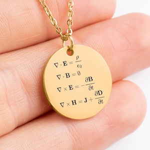 Op de afbeelding: Goudkleurige hangerketting met een fijne ketting. De ronde hanger toont zwarte tekst met wiskundige vergelijkingen. Een modieus accessoire.