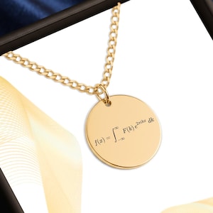 May include: A gold-toned circular pendant necklace featuring a delicate chain and a flat, round charm. The pendant is engraved with the mathematical Fourier transform formula f(x) = integral from negative infinity to infinity of F(k) e^2piikx dk.