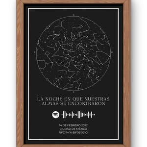 Może przedstawiać: Oprawiony wydruk z czarnym tłem i białym wzorem mapy gwiazd. Wyświetlany jest tekst "LA NOCHE EN QUE NUESTRAS ALMAS SE ENCONTRARON", a także kod Spotify oraz szczegóły daty i lokalizacji. Rama jest drewniana.