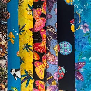 May include: A collection of patterned fabric rolls. Designs include pink diamonds with dog silhouettes, horseshoes, animal prints, fish, butterflies, ladybugs, flowers, and dog and cat faces. The fabrics are in various colors.