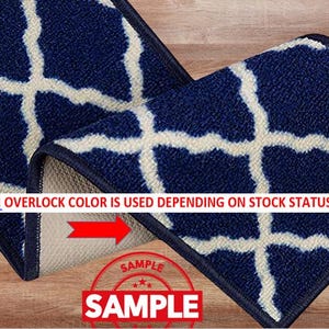 May include: Close-up of a section of a navy blue rug with a white geometric pattern. The rug has a dark blue border. The text "!!! OVERLOCK COLOR IS USED DEPENDING ON STOCK STATUS." is visible. A red arrow and the word "SAMPLE" are also visible.