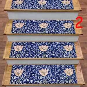 Puede incluir: Peldaños de escalera con un estampado floral. Las huellas presentan un fondo azul marino con un diseño repetido de flores color melocotón y follaje blanco. Las huellas de la escalera son rectangulares y se colocan en escaleras de madera.