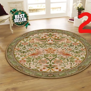 Op de afbeelding: Een rond vloerkleed met een gedetailleerd botanisch patroon van vogels, bloemen en bladeren in tinten groen, perzik en crème. Het kleed heeft een brede decoratieve rand met een herhalend bladmotief en een centraal ontwerp met vogels.