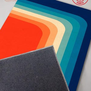 May include: A retro-style rug with a vibrant color palette. The design features a series of curved stripes in shades of orange, cream, teal, and blue. The rug's edge is visible, revealing a gray backing. A "SAMPLE" stamp is in the upper right corner.