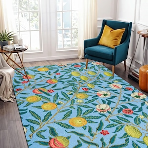 Op de afbeelding: Een blauw tapijt met een bloemenpatroon met groene bladeren, gele en oranje vruchten en roze bloemen.