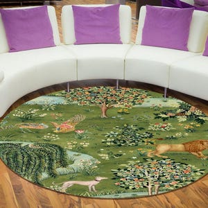 May include: A round area rug with a detailed pastoral scene. The rug features a green background with trees, flowers, and various animals, including a lion and a dog. The rug is placed on a hardwood floor.