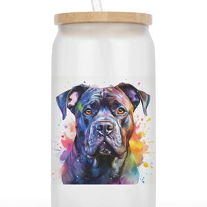 Op de afbeelding: Een witte glazen beker met een houten deksel en een doorzichtig rietje. De beker heeft een aquarel schilderij van een zwarte hond met kleurrijke verfspatten. De hond heeft bruine ogen en een serieuze uitdrukking.
