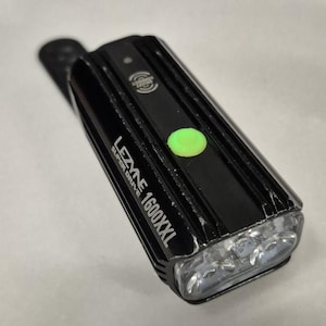 May include: Black Lezyne Super Drive 1600XXL bike light with a green power button. The light has a rectangular shape with three clear lenses and the text "Lezyne Super Drive 1600XXL".