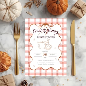 Op de afbeelding: Een Friendsgiving diner uitnodiging met een roze en witte geruite achtergrond. De uitnodiging bevat de tekst "Friendsgiving Dinner Invitation" en details van het evenement. Een gouden vork en mes zijn zichtbaar. Pompoenen en een geschenkdoos.