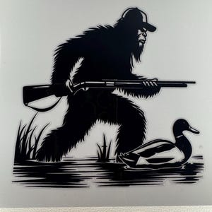 May include: Black and white graphic of Bigfoot, wearing a cap and holding a rifle, stalking a duck in water. The image is a silhouette, with details of the fur, rifle, and duck visible.