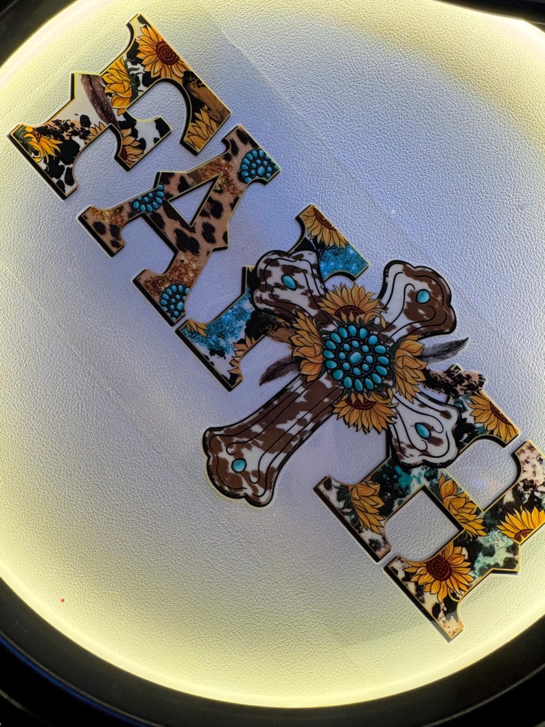 May include: Wooden sign spelling "FAITH" with a cross. The letters and cross feature a mix of patterns including sunflowers, cowhide, and leopard print. Turquoise accents are incorporated into the design, creating a rustic, country aesthetic.