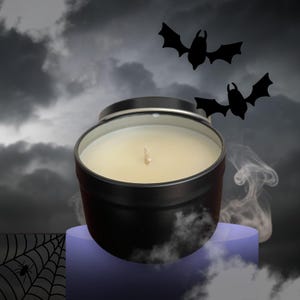 May include: A black candle tin with a lit wick, filled with a creamy wax. The candle sits on a purple stand against a cloudy, dark sky background. Two black bat silhouettes are in the sky, with wisps of smoke.