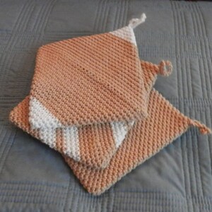 Può includere: Due presine da forno in maglia marrone e bianca con un motivo a righe.