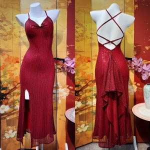 May include: A red sequined formal dress with a high slit and spaghetti straps. The dress has a low back with crisscross straps. The dress is displayed on a mannequin. The dress is floor length.